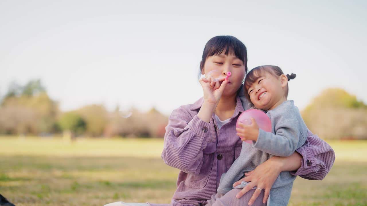 妈妈和小女儿在公园里玩泡泡视频素材