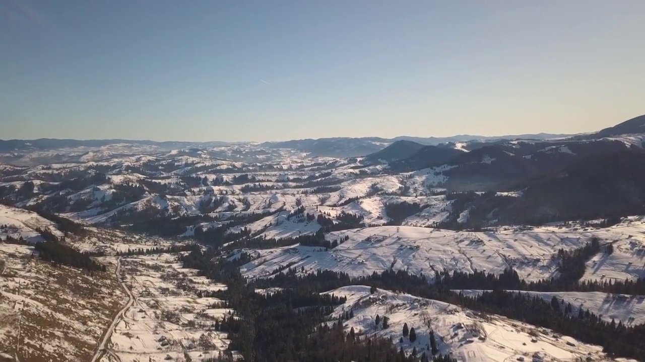 鸟瞰图，在乌克兰的喀尔巴阡山脉，冬天白雪覆盖的山丘上散落着房屋视频素材