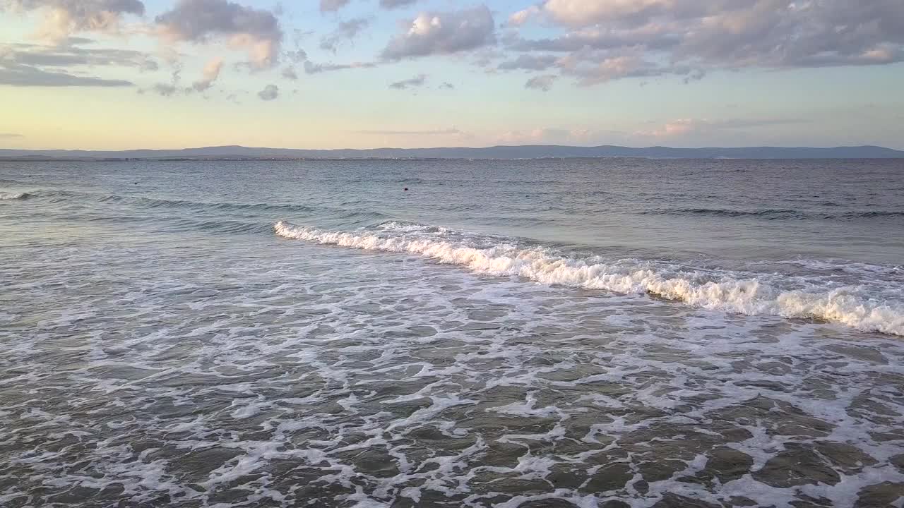 鸟瞰图的海面与蓝色的水波浪下日落的天空。视频素材