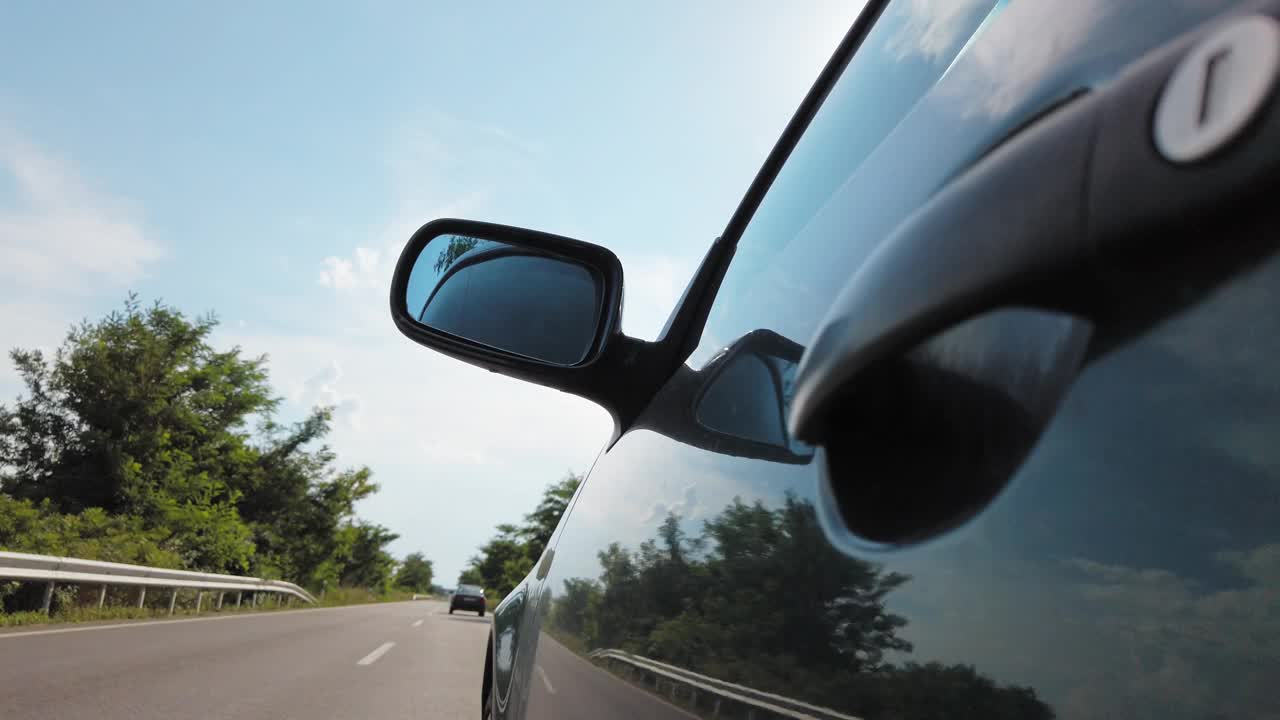 一辆黑色跑车的后视图行驶在田野间的乡村道路上，一幅乡村风景的景象视频素材