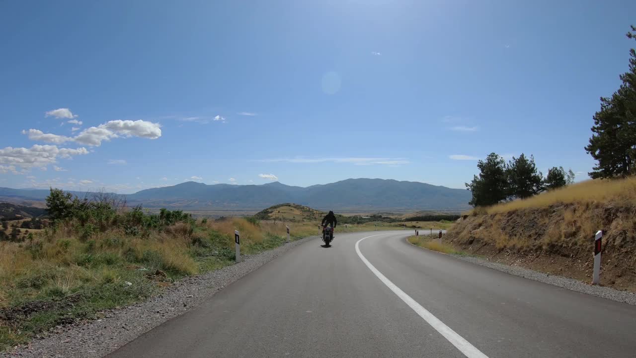 骑摩托车的特技在乡村山路上骑自行车，在摩托车上做前轮特技视频素材