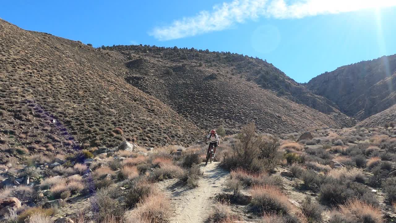 一名男子山地自行车手沿着狭窄的沙漠轨道行驶视频素材