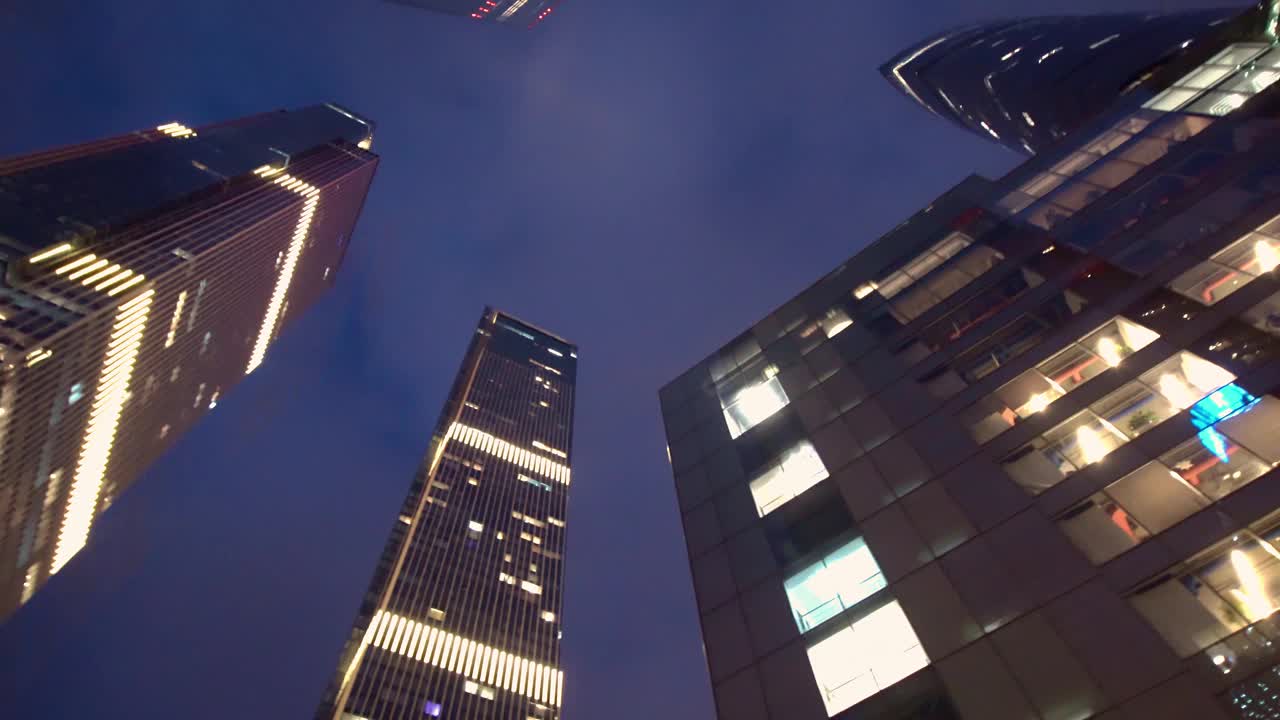 从市中心的摩天大楼和塔楼底部向上看夜景。视频素材