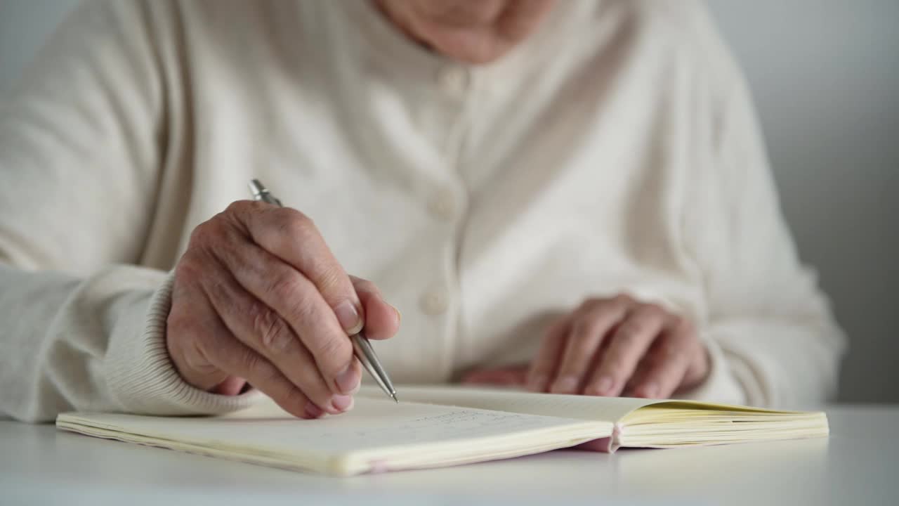 老妇人用钢笔在笔记本上写下详细的笔记视频素材