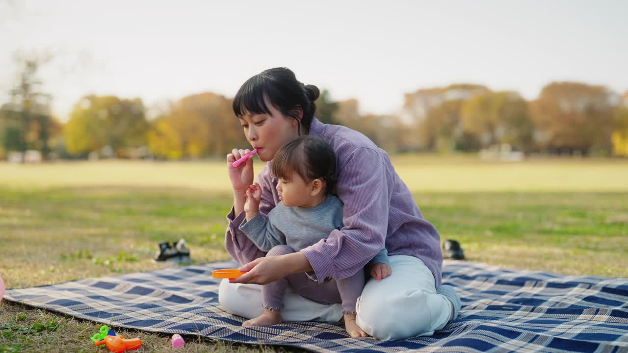 妈妈和小女儿在公园里玩泡泡视频素材