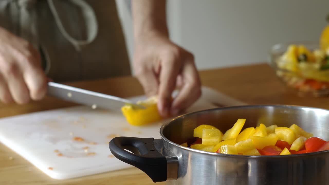 男人在家里煮新鲜的食物。特写厨师用手切辣椒的慢动作。男性专业人士在厨房用刀准备蔬菜视频下载