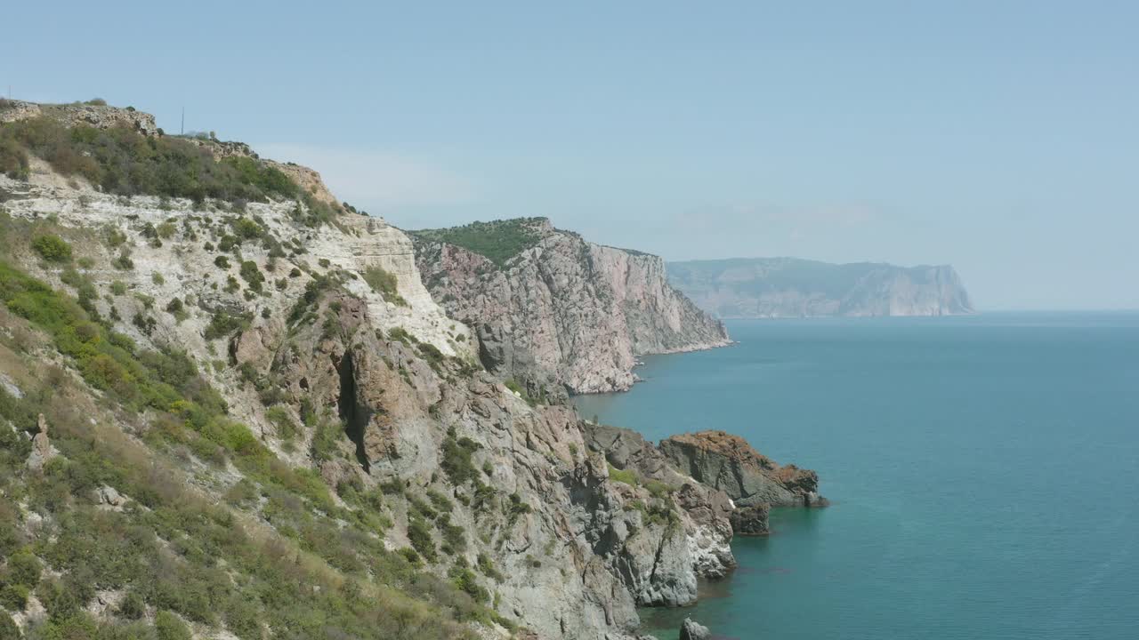 风景如画的海岸、悬崖峭壁和蔚蓝的大海。行动。有岩石海岸的海景。克里米亚黑海岩石海岸的惊人美景视频素材