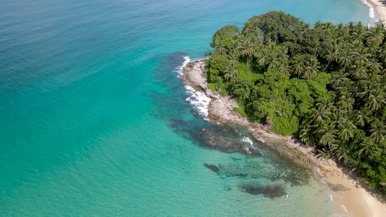 无人机拍摄的4k鸟瞰图海洋蓝色的海浪撞击海岸的岩石，泰国普吉岛素林海滩。视频下载