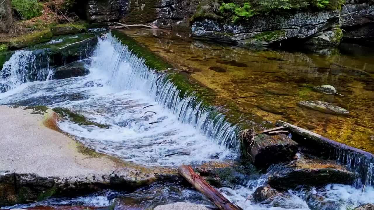 一个美丽的小瀑布从山上森林的河流。胶片颗粒视频素材