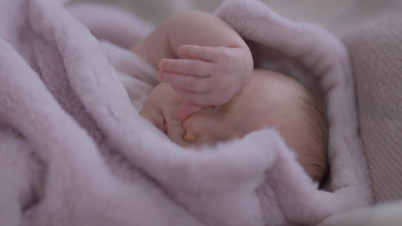 特写无忧无虑熟睡的女婴用小手揉眼睛。迷人的白种可爱的婴儿肖像躺在舒适的床上午睡在家里的室内。快乐和童年。视频素材