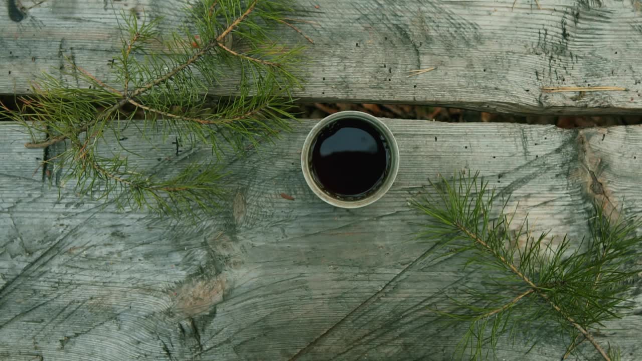 松枝丛中的一张森林餐桌上，用绿色玻璃杯盛着咖啡和茶。咖啡饮品的概念。阳光明媚的秋天心情。从上面的观点视频素材