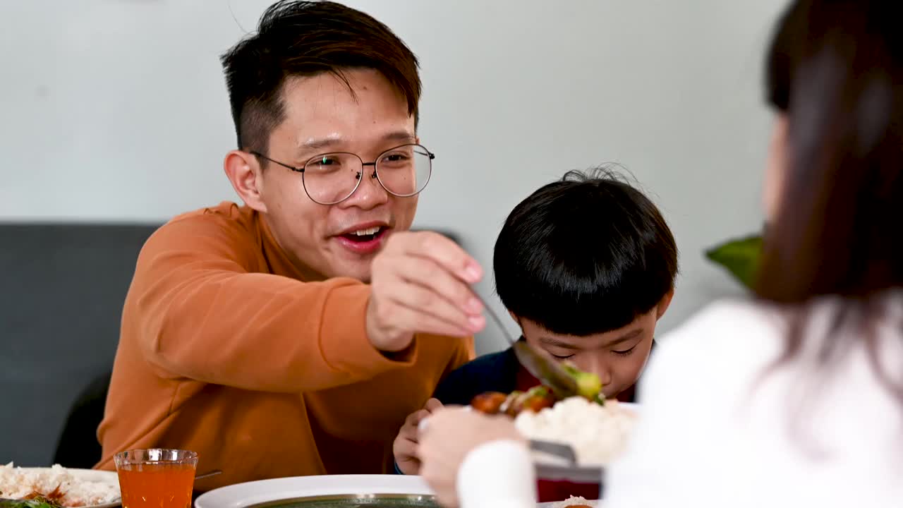 中国农历新年，一名亚洲男子在家中享用团圆饭时，与母亲分享食物视频素材