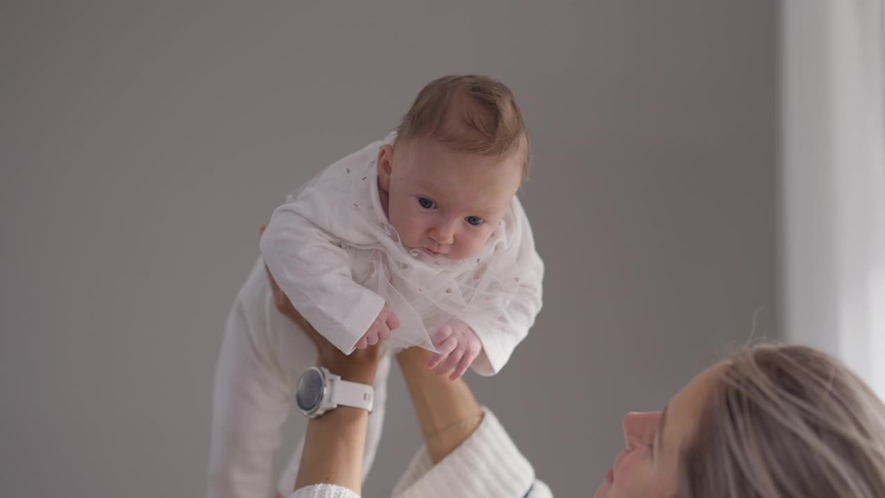 快乐的白人女婴在年轻的母亲手中慢动作说话。无忧无虑的小宝贝女儿的肖像享受休闲与爱的女人在家里在室内。家庭和初级阶段。视频素材