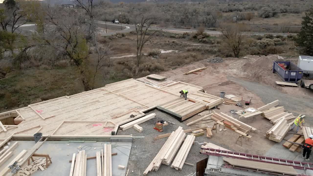 在一个新的房屋建筑工地，木匠用一把钉枪从木框架墙上钉下来。视频素材