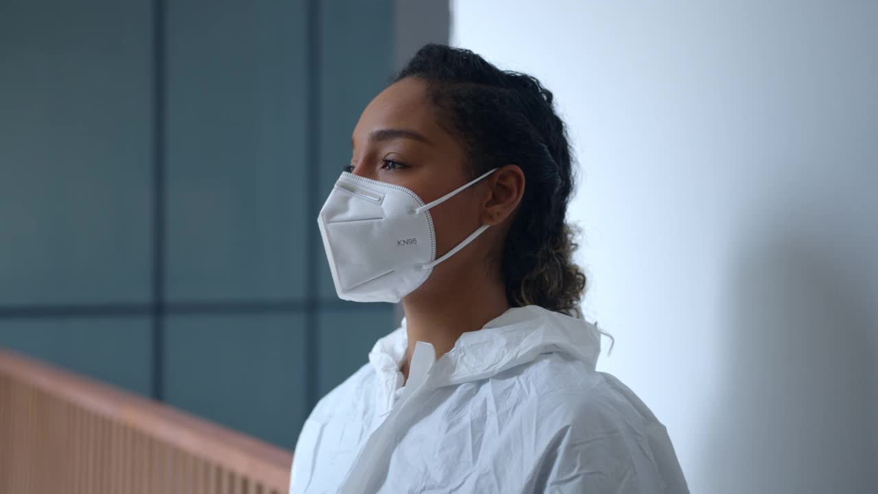 近距离的女一线工作人员穿着防护生物安全元素靠在墙上精疲力竭的医院视频素材