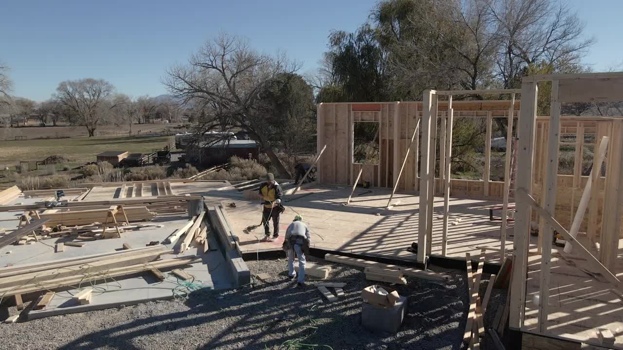 无人机住宅建筑工地与三个高加索框架木匠工作的墙壁视频素材