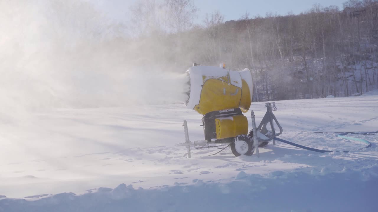 冬季星期天，滑雪场的雪炮。造雪机在森林、蓝天制造人工雪。涡轮在冷空气中喷水。山地运动中滑雪道的准备视频素材