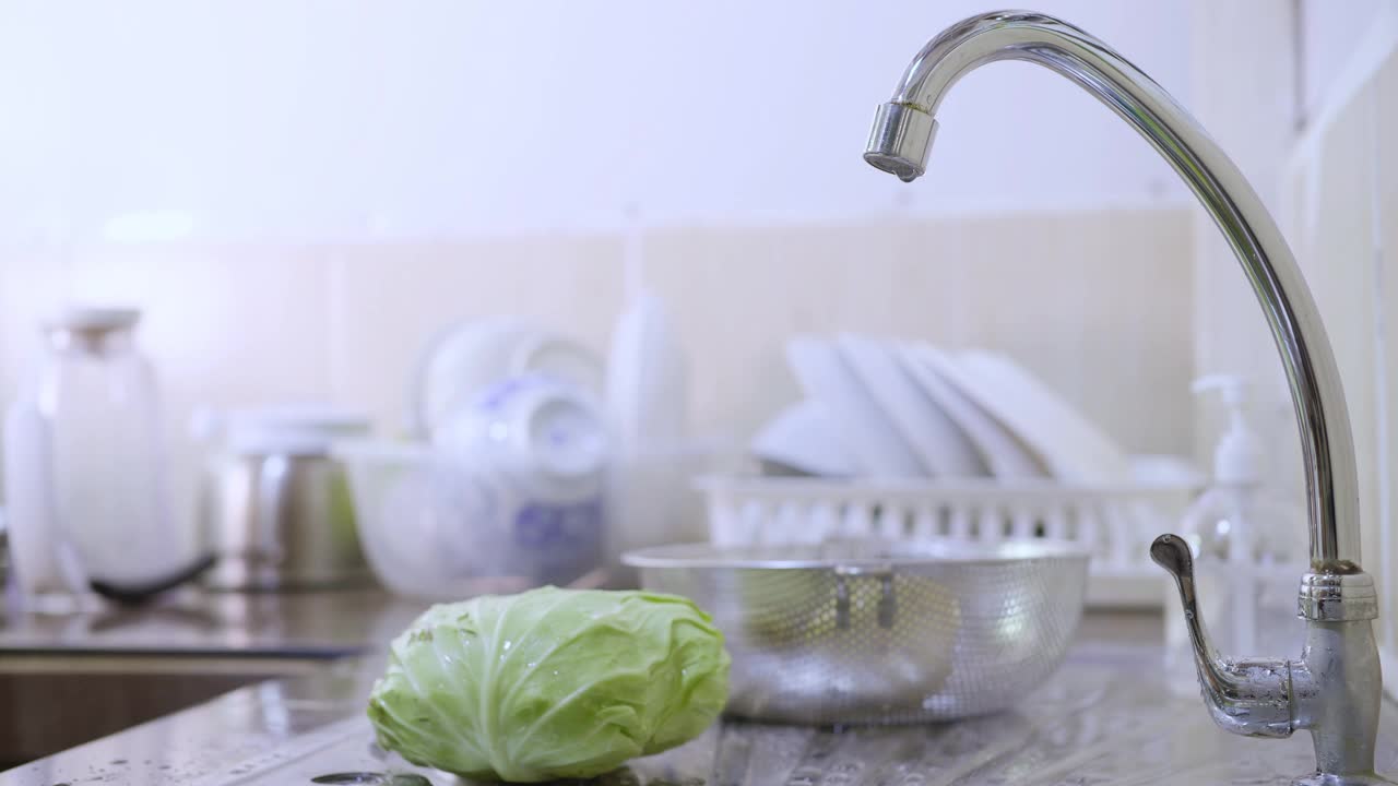 在厨房的水槽里，女性在流动的水流下洗着卷心菜视频素材