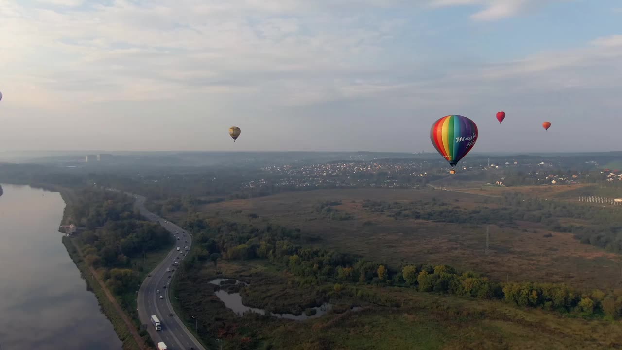 空中飞行的彩色气球在一个大的河流平静的水在日落在高海拔。云倒映在水中。跟踪无人机飞行视频素材