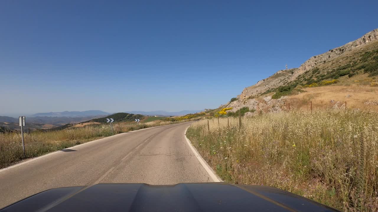 POV汽车行驶在笔直的两路旧沥青公路通过一座山在西班牙视频素材