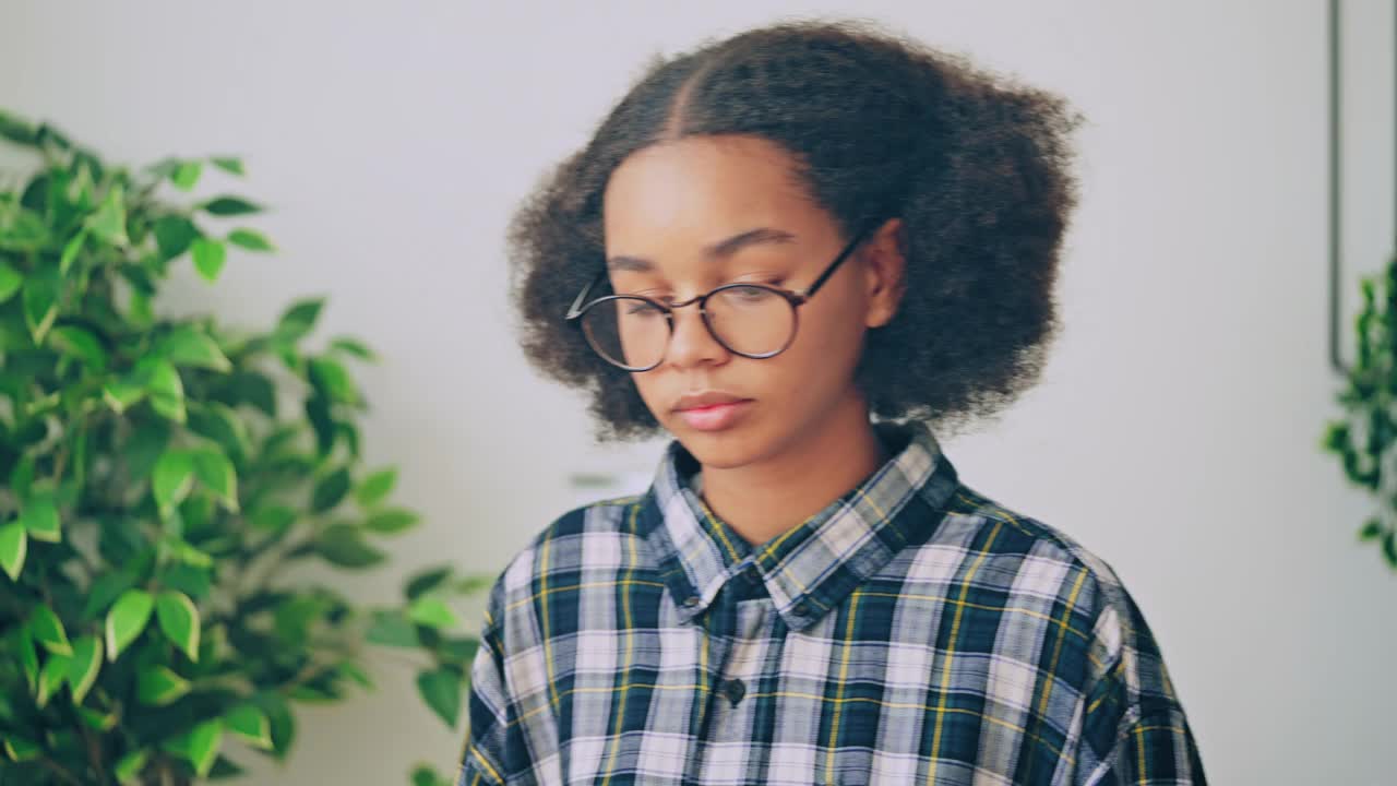 戴眼镜的聪明黑人少女打开笔记本电脑，做学校的作业视频素材