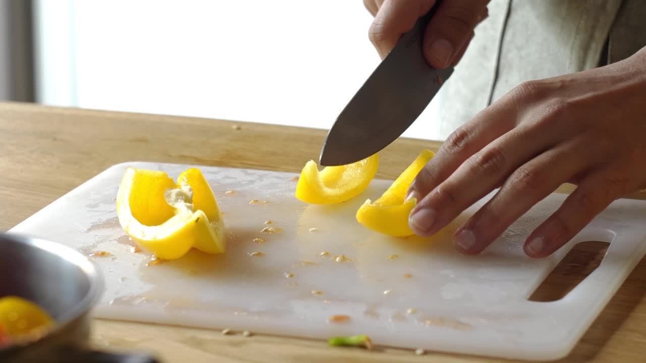 男人在家里煮新鲜的食物。特写厨师用手切辣椒的慢动作。男性专业人士在厨房用刀准备蔬菜视频下载