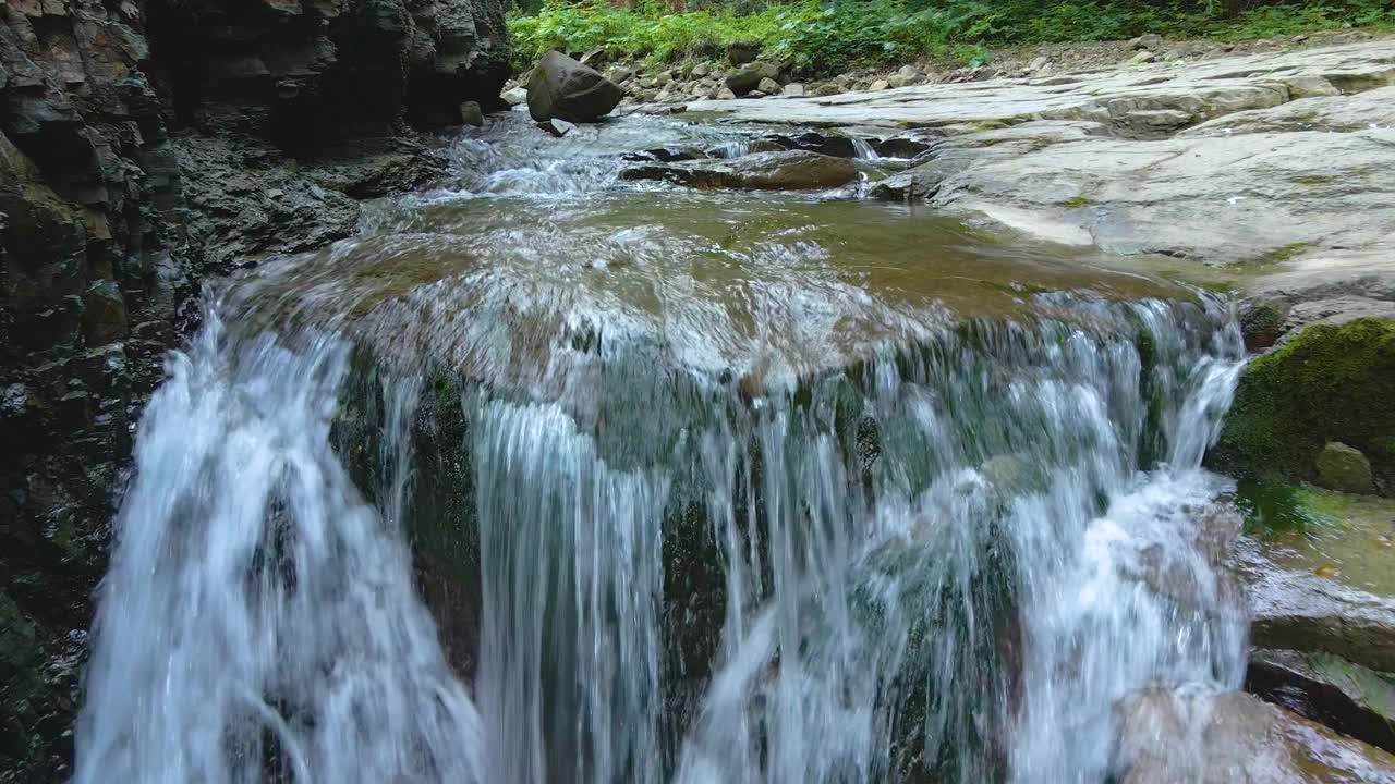 瀑布在山上的河流与白色泡沫水下降下来的岩石形成在夏季森林视频素材