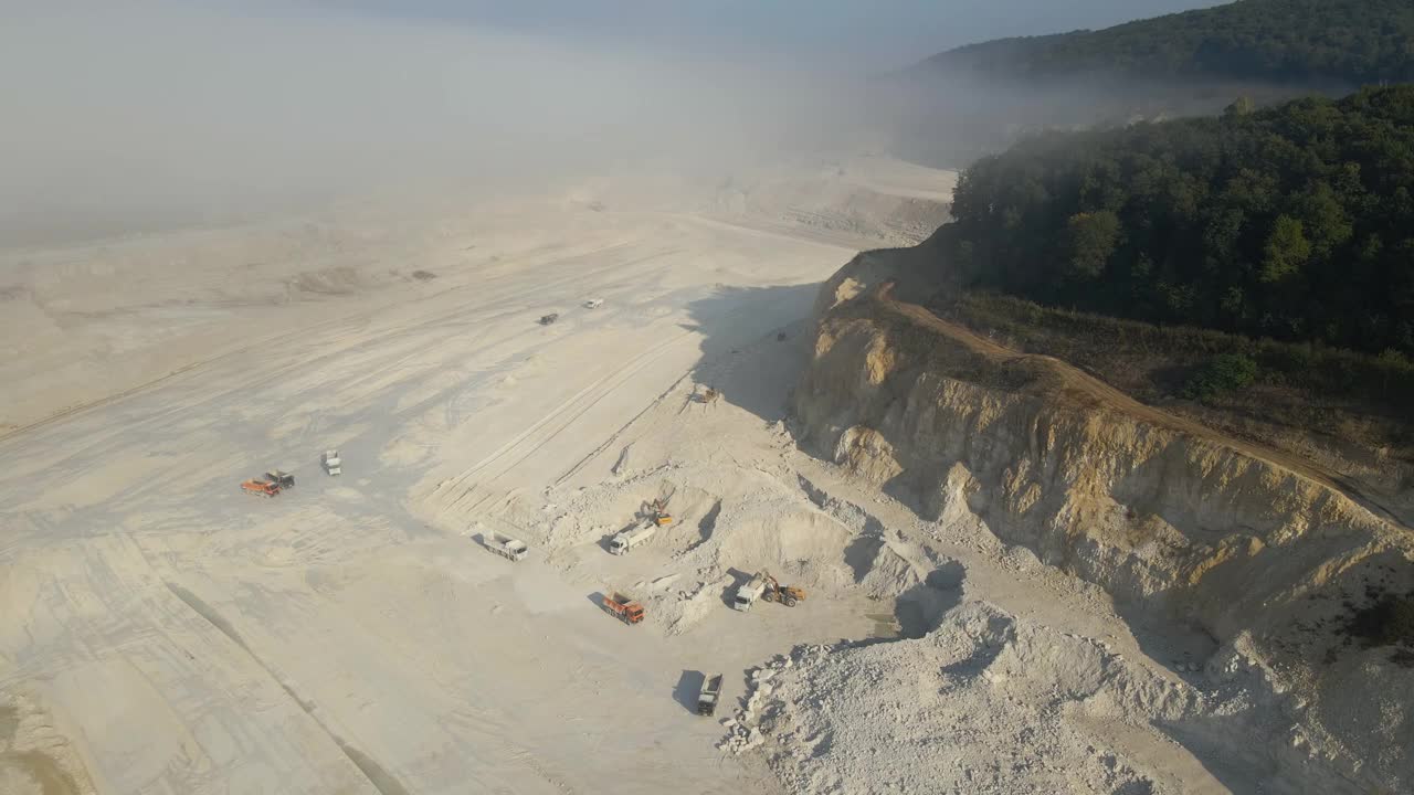 建筑工业用挖掘机和自卸卡车开采石灰石材料的露天矿区鸟瞰图视频素材