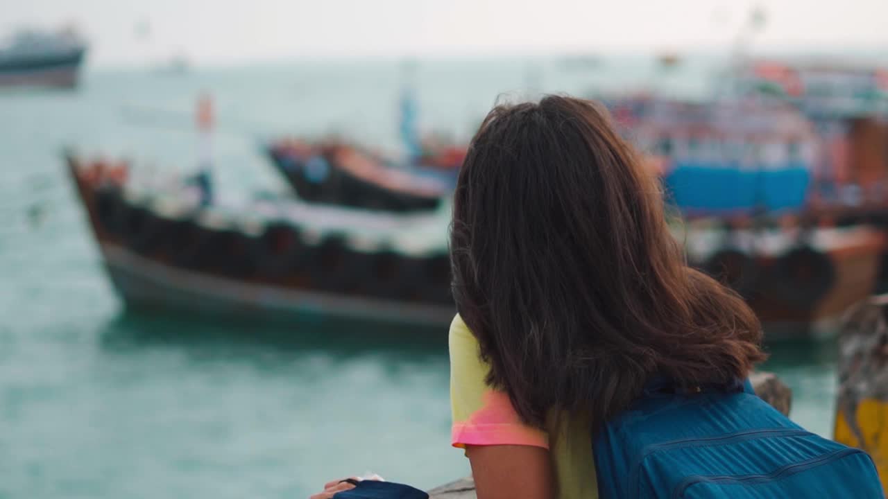 平和的女性旅行者带着袋子在海边享受呼吸新鲜空气和观看帆船。在印度古吉拉特邦的德瓦卡视频素材