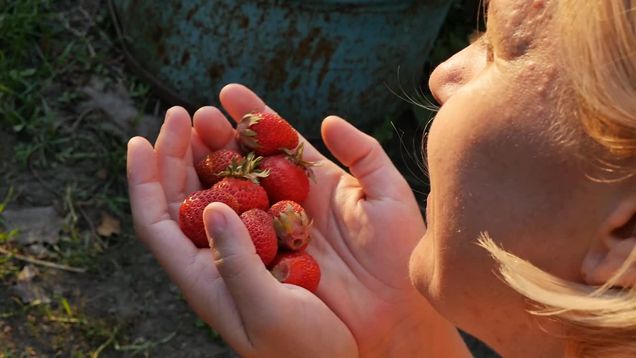 女人用手闻着草莓的香味。慢动作视频。特写镜头。视频素材