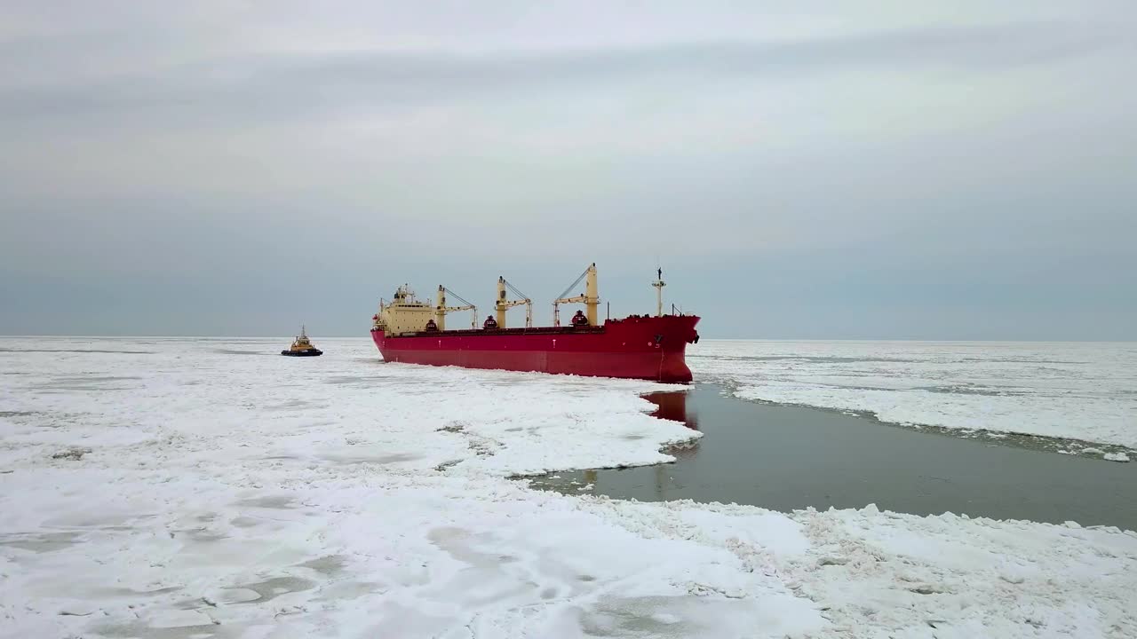 空中史诗般巨大的钢铁破冰船靠船首破冰，漂浮在巨大的浮冰上。在冰冻的航道上维持航行。自行式专用船红色船视频素材