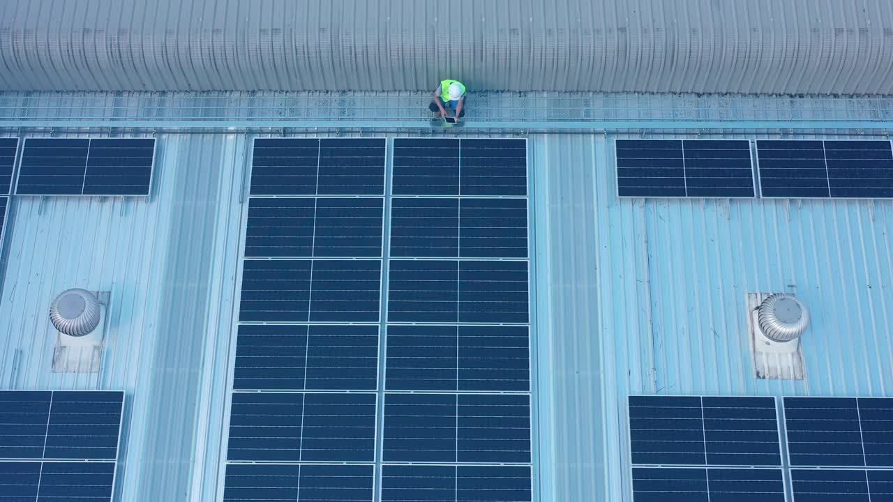 太阳能工程师在工厂屋顶行走检查太阳能电池板的鸟瞰图视频素材