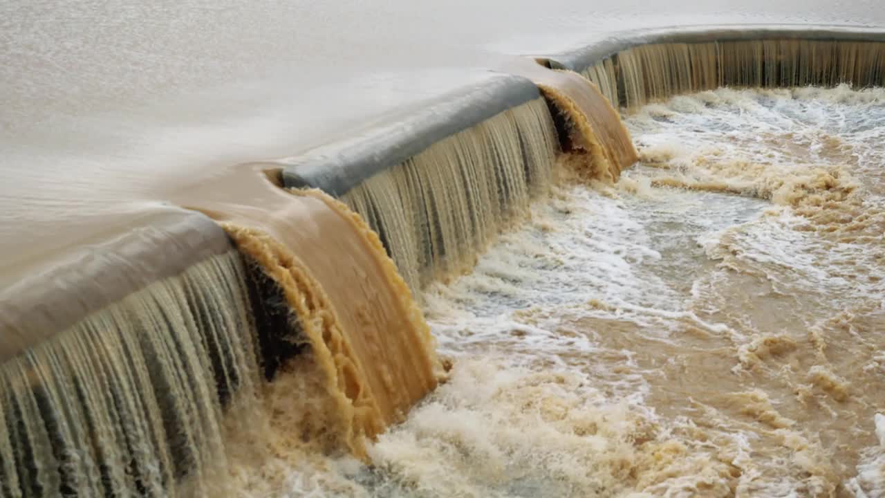 水坝里的棕色水流入溢洪道视频素材