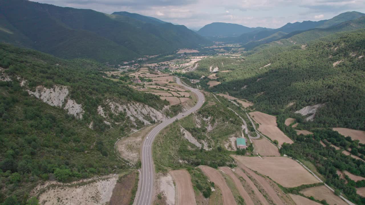 无人机拍摄的高山上柏油路的美景。山脉消失在天空中，天空略多云，但山峰被太阳照亮。视频素材