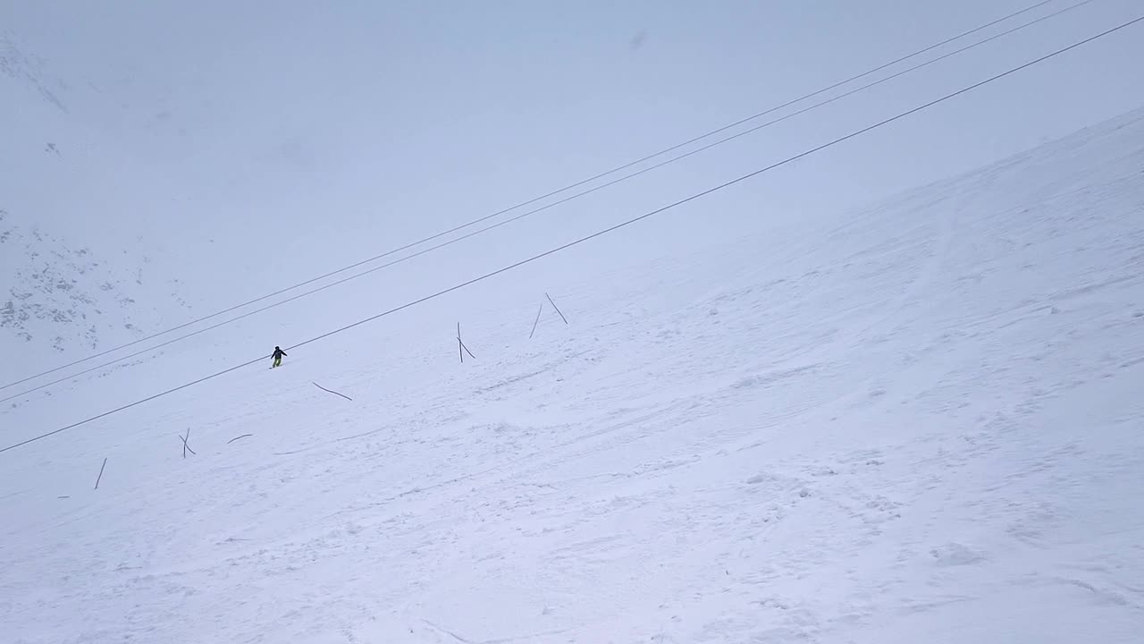 缓慢的运动。无人驾驶飞机射击。在下雪的天气里，一个孤独的滑雪者沿着山坡向下滑行的俯视图视频素材