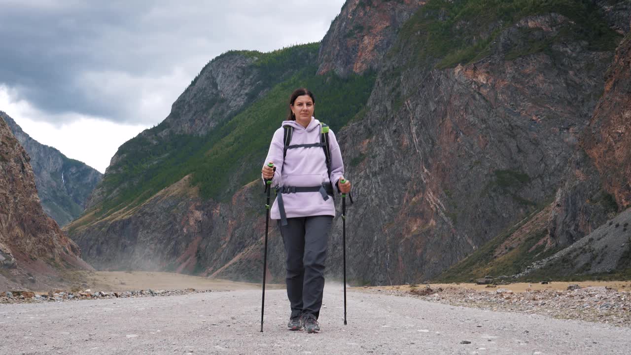 在落基山脉背景的地面道路上用登山杆远足的游客视频素材