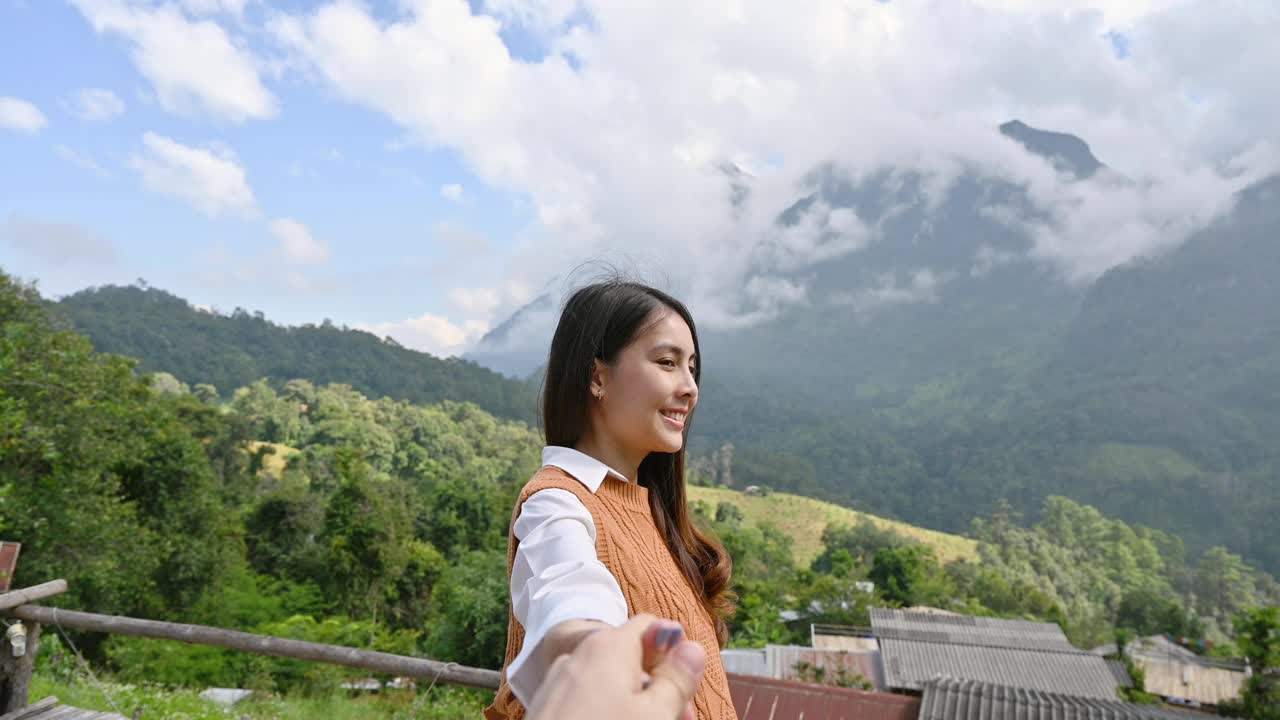 亚洲女子牵着男友的手，在江道的观景点欣赏山上的山景视频素材