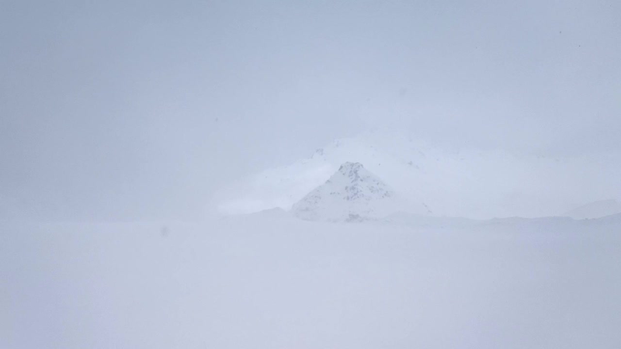 缓慢的运动。在狂风大作的暴风雪中看到积雪覆盖的山峰视频下载