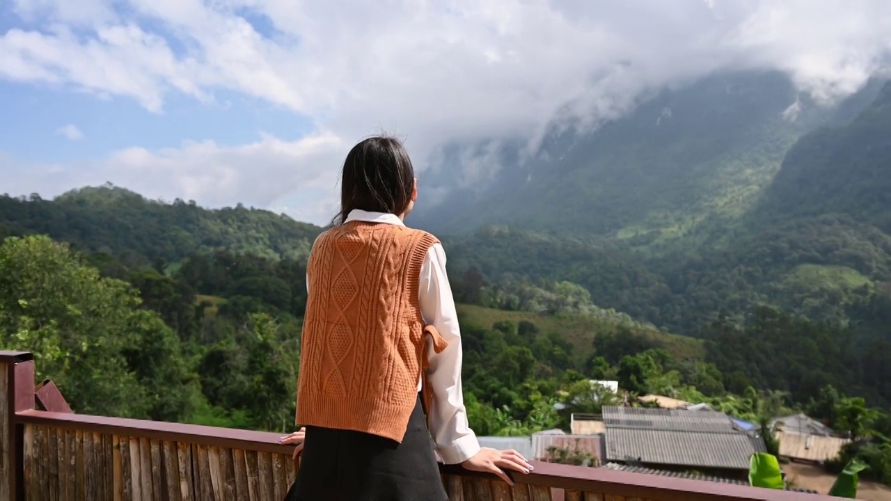 美丽的亚洲女人站在阳台上享受山景在Chiang Dao视频素材