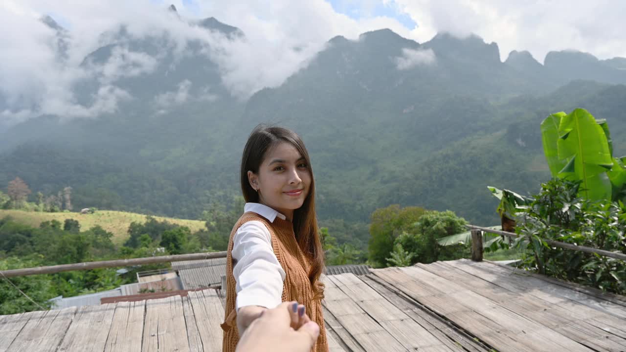 亚洲女子牵着男友的手，在江道的观景点欣赏山上的山景视频素材