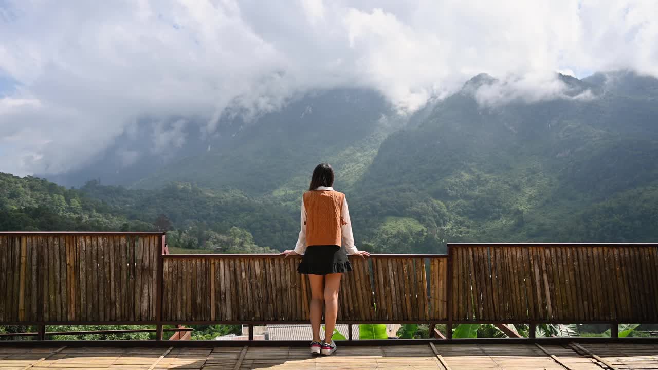 美丽的亚洲女人站在阳台上享受山景在Chiang Dao视频素材