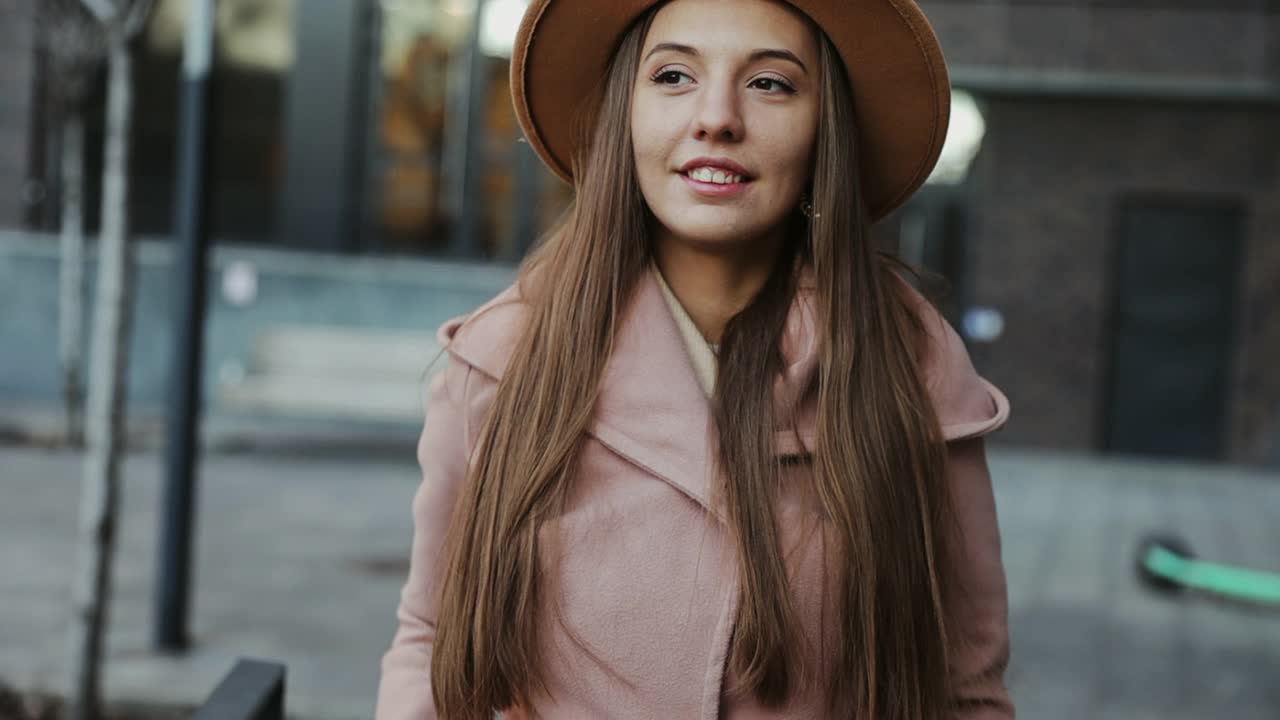 以城市为背景，穿着外套戴着圆帽的漂亮年轻女子视频素材