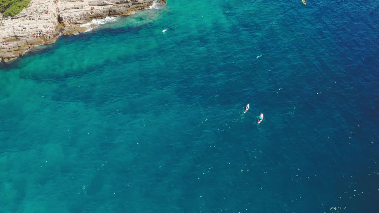 人们在度假村的岩石海滩上冲浪和皮划艇视频素材