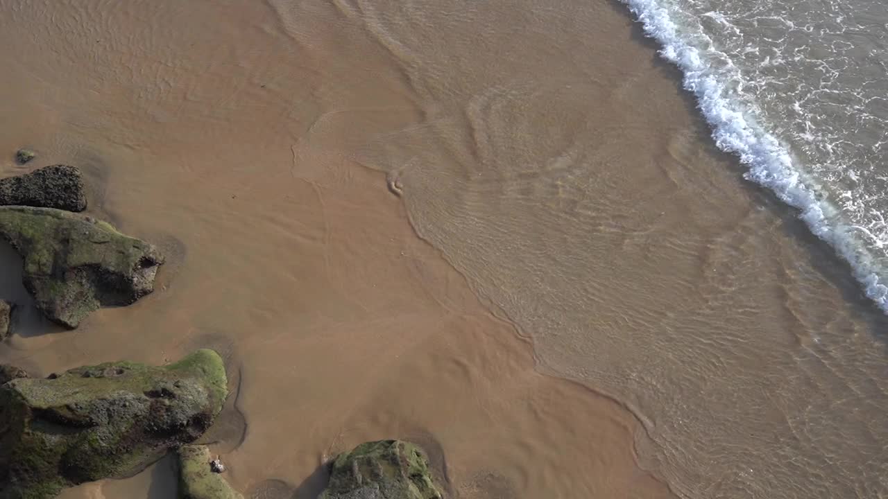 岩石旁边的海浪的鸟瞰图。在波涛汹涌的飞机上看海，海浪平静的大海在夏天视频素材