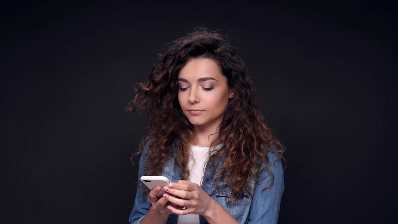 沉思的卷发女人在智能手机上写信息视频素材