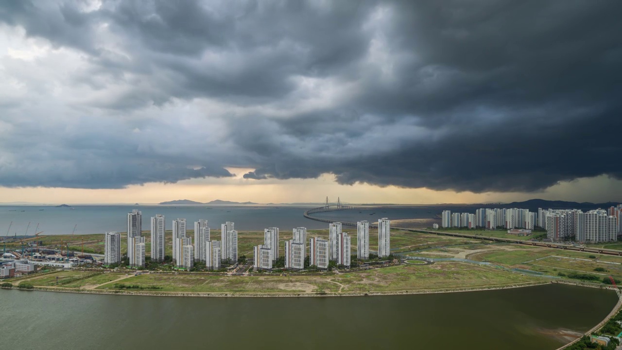 ▽白天=仁川松岛国际商圈(延寿区)松岛地标城市(Songdo Landmark City)的西海仁川大桥和松岛海滨附近的公寓上空乌云密布视频素材