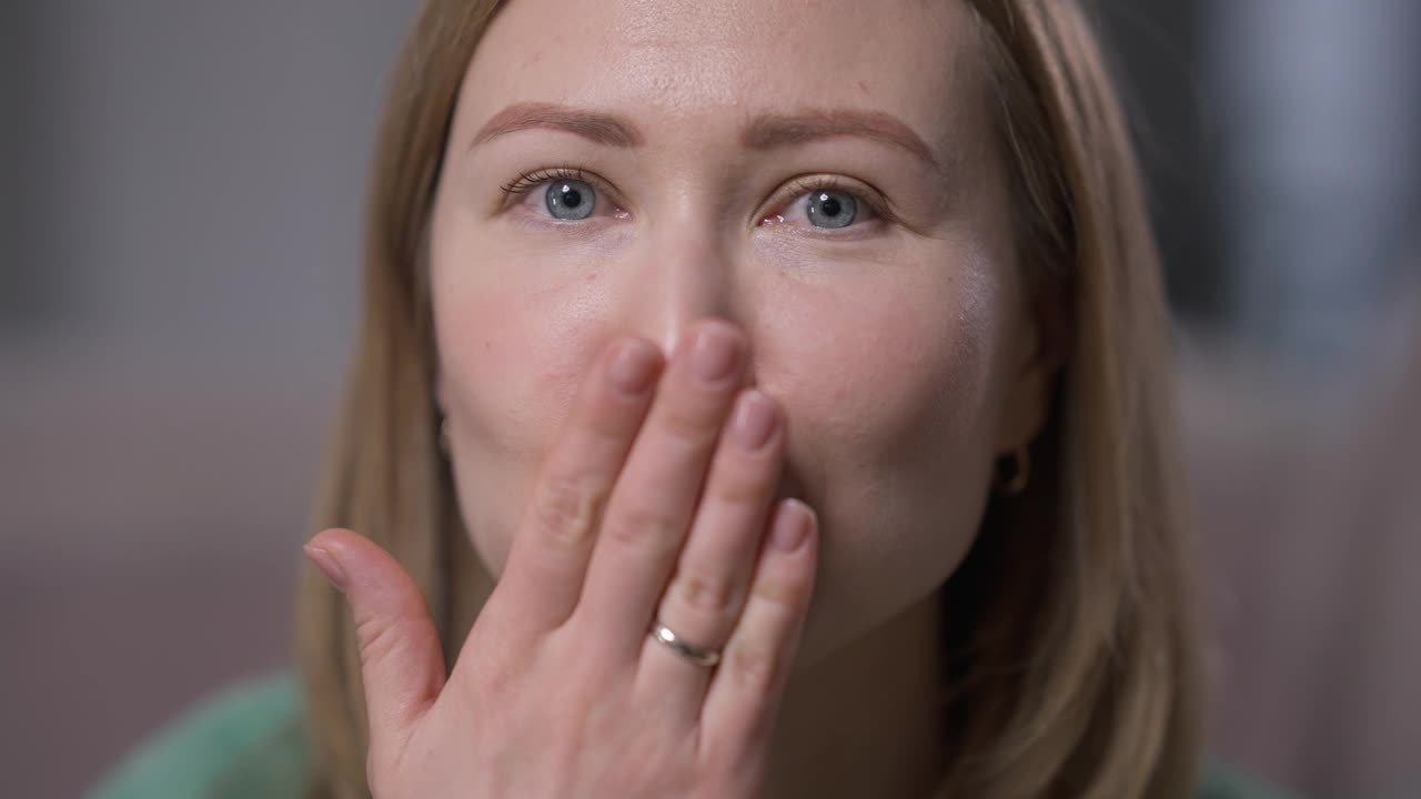 前视图特写轻浮的年轻白人妇女手势空气吻微笑看着相机。头像的风骚美丽苗条女士摆在慢动作调情室内。视频素材