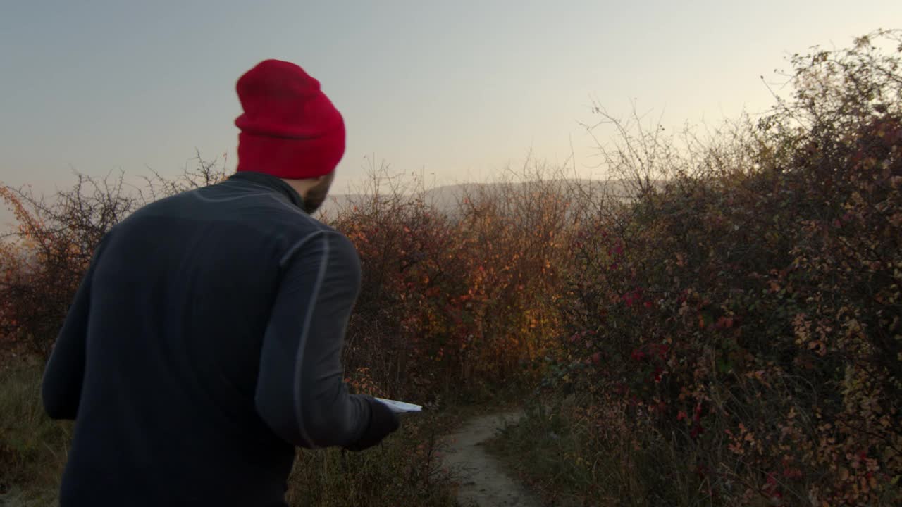 在阳光明媚的秋日早晨，一个中年男子在灌木丛中奔跑下山。夕阳清晰的蓝天在背景上视频素材