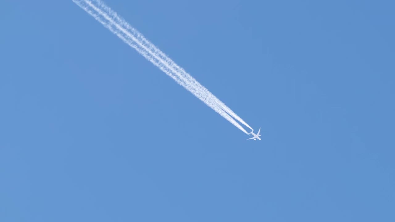 远处的喷气式客机在晴空万里的高空飞行，留下白色的烟雾和尾迹。航空运输的概念视频素材