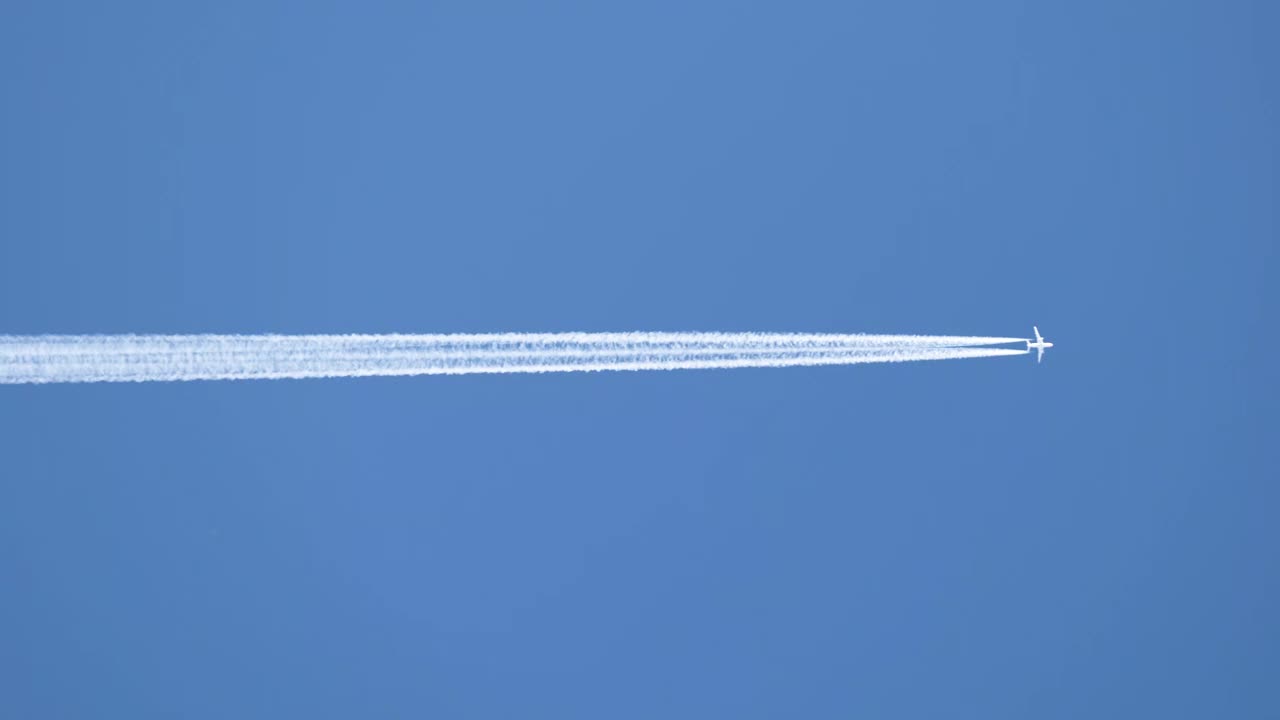 远处的喷气式客机在晴空万里的高空飞行，留下白色的烟雾和尾迹。航空运输的概念视频素材